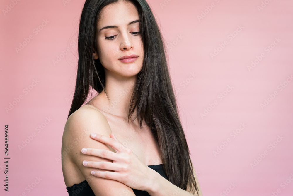 Fototapeta premium Calm woman with makeup in studio touching her shoulder