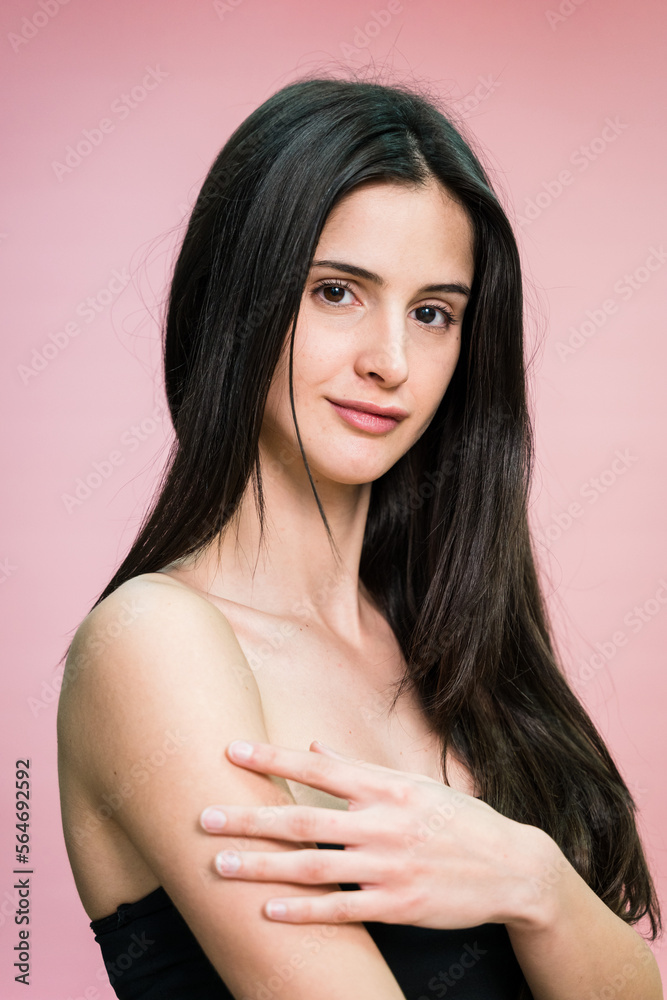 Calm woman with makeup in studio touching her shoulder Calm woman with makeup in studio touching her shoulder