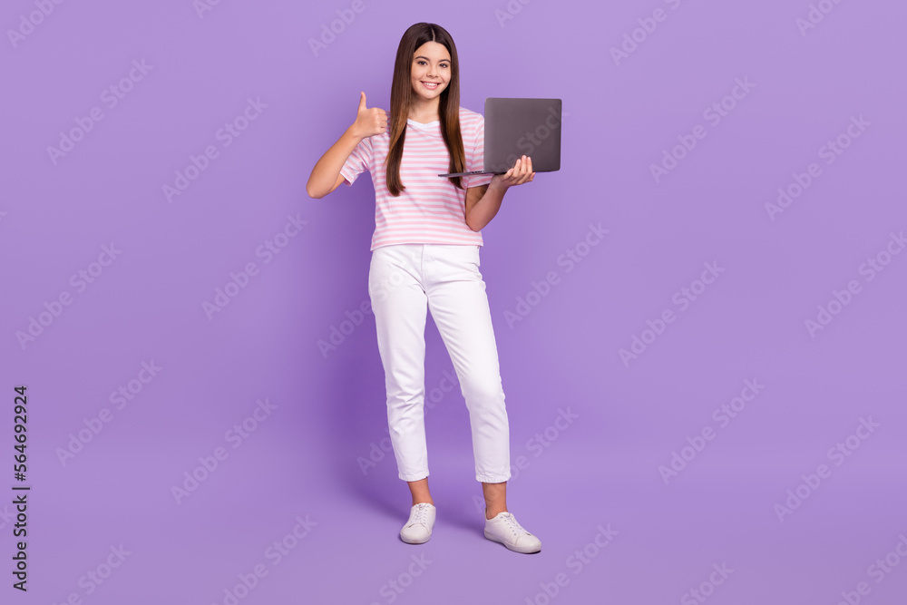 Full size photo of cute schoolgirl hold netbook demonstrate thumb up isolated on violet color background Full size photo of cute schoolgirl hold netbook demonstrate thumb up isolated on violet color background