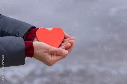 Women s hands hold a red heart on a light background.The concept of Valentine s Day  love.