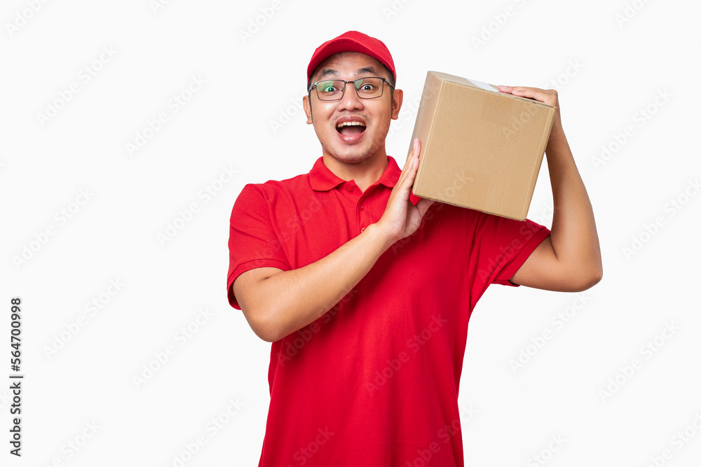 Smiling asian courier in red uniform holding package on shoulder, give client their order