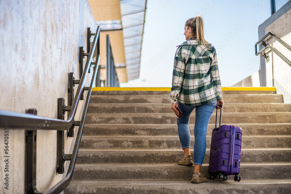 Woman with suitcase and ticket going up by stairs in the train station. Woman with suitcase and ticket going up by stairs in the train station.