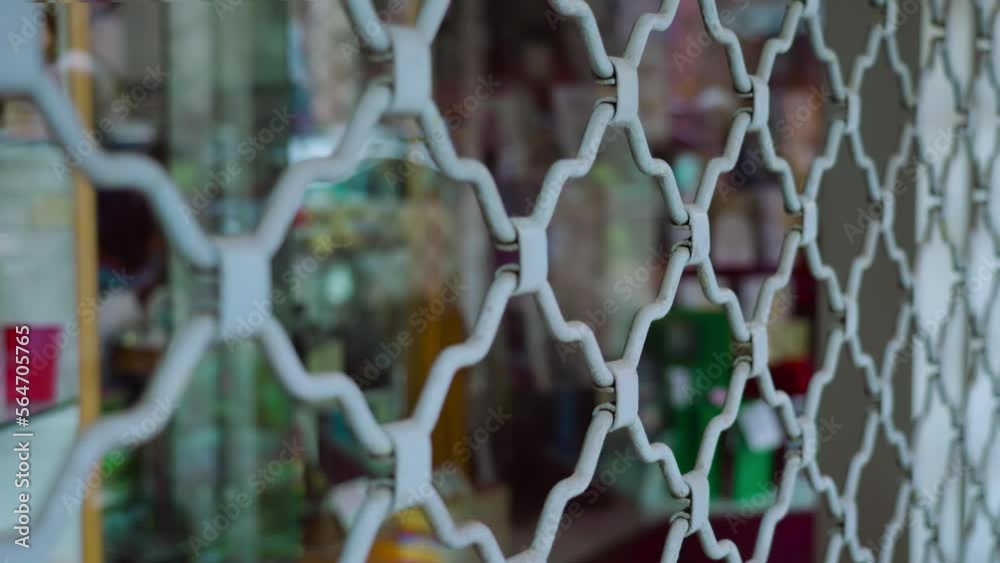 Metal bars security shutter lacy grate protects shop window reflecting street situated on historical building ground floor Metal bars security shutter lacy grate protects shop window reflecting street situated on historical building ground floor