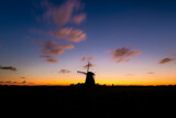 Windmills in the Netherlands. Historic buildings. Agriculture. Summer landscape during sunset. Bright sky and the silhouette of a windmill. Photography for design.