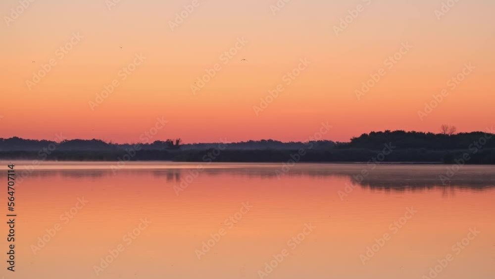 Sunrise over lake and beautiful morning landscape. Morning sun breaks through the thick fog. Early morning on calm river with fog. Fantastic foggy river in the golden sunlight on water surface Sunrise over lake and beautiful morning landscape. Morning sun breaks through the thick fog. Early morning on calm river with fog. Fantastic foggy river in the golden sunlight on water surface