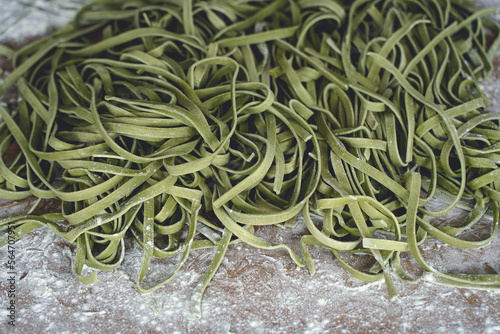 Fresh pasta. Homemade italian raw fettuccine pasta with spinach on wooden table background