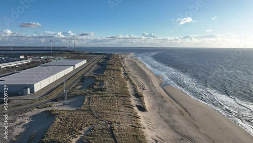 Aerial drone video showcasing the contrast of natural beauty of the beach, dunes and the ocean on the Maasvlakte with the industrial zone, highlighting the waterfront and transportation industry. photo