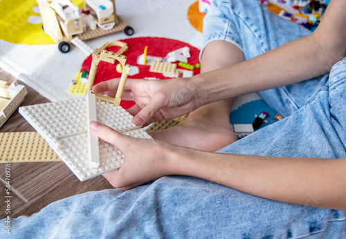 Close-up of a hand and plastic building blocks. Child holding colorful toy blocks at home, sitting on the floor in the living room. builds and assembles. educational games