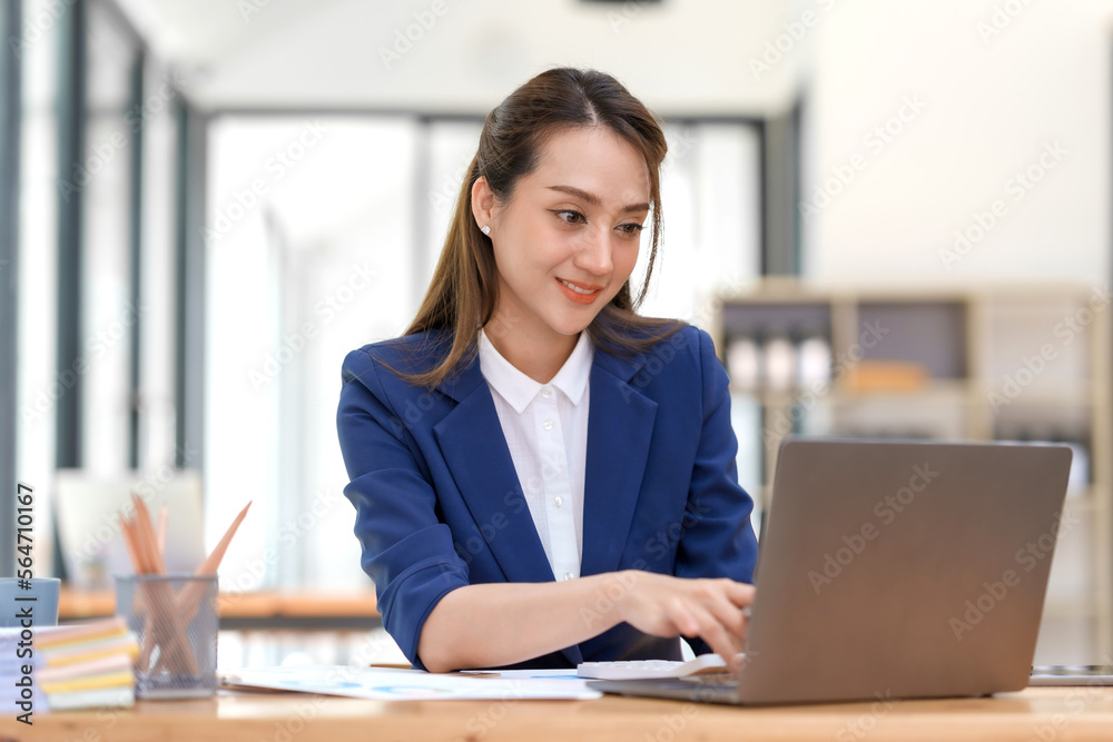 Smiling and attractive asian businesswoman enjoying working using laptop computer at office. Smiling and attractive asian businesswoman enjoying working using laptop computer at office.