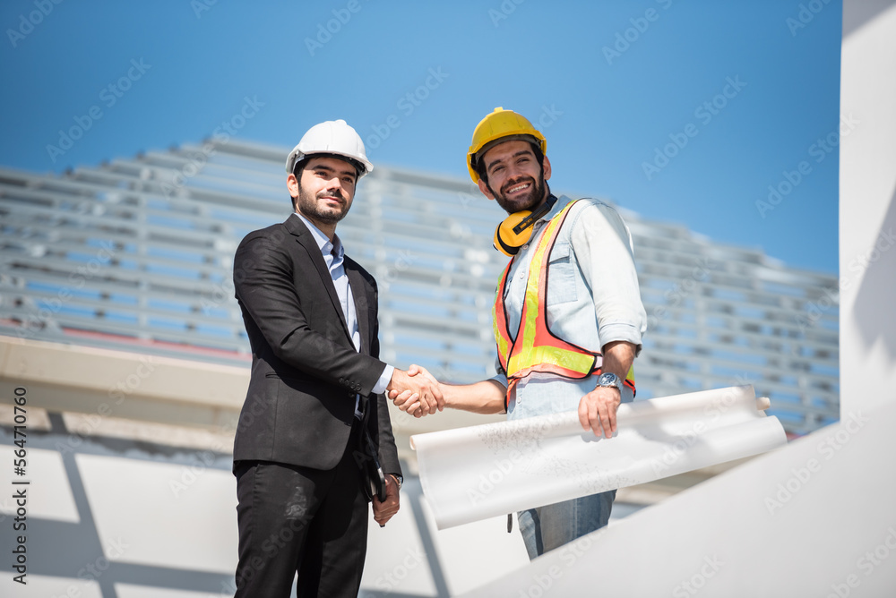 Construction engineer and architect team working together with blueprints discuss onthe rooftop outdoor at construction site. Construction engineer and architect team working together with blueprints discuss onthe rooftop outdoor at construction site.
