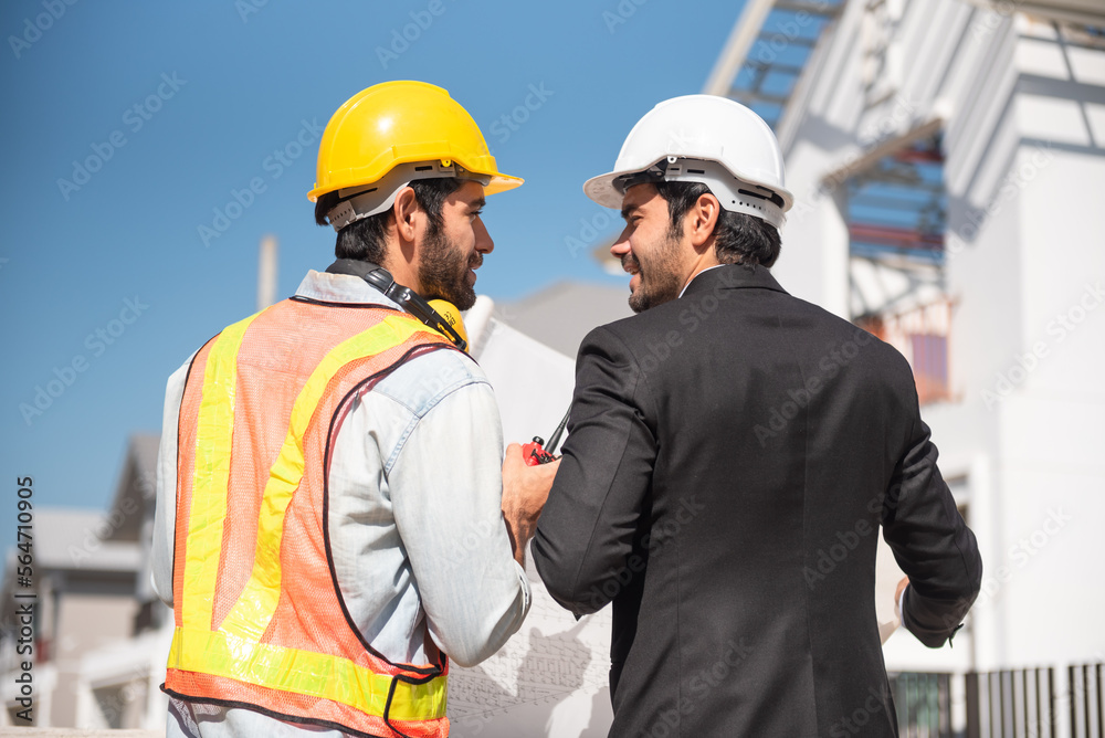 Teamwork men in construction site, Two civil engineer in safety helmet hard hat using digital tablet and blueprint working while standing at factory. Teamwork men in construction site, Two civil engineer in safety helmet hard hat using digital tablet and blueprint working while standing at factory.
