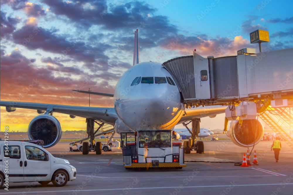 Fototapeta premium Airplane execute push back operation at airport. Aircraft service for flights before departure in the evening at sunset.