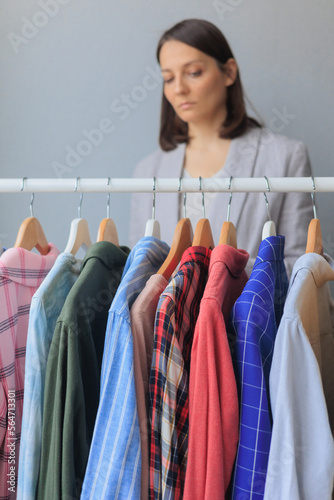thoughtful woman does not know what to wear. selects clothes in wardrobe or store. shopping and selection of look for work and meetings. female stylist helps to buy clothes. recycling of textiles