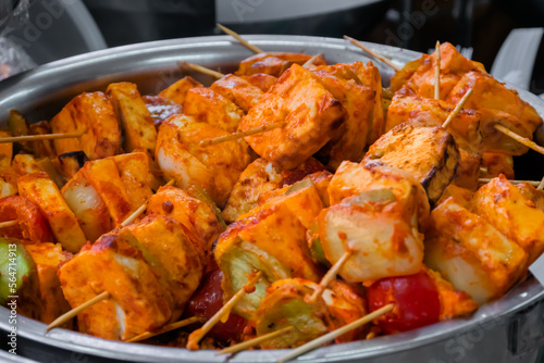 Fresh colorful vegan Paneer Tikka - Indian appetizer made with cubes of paneer, tomato, zucchini, onion, pepper marinated with yogurt, spices - close up view. Vegetarian, oriental, street food concept