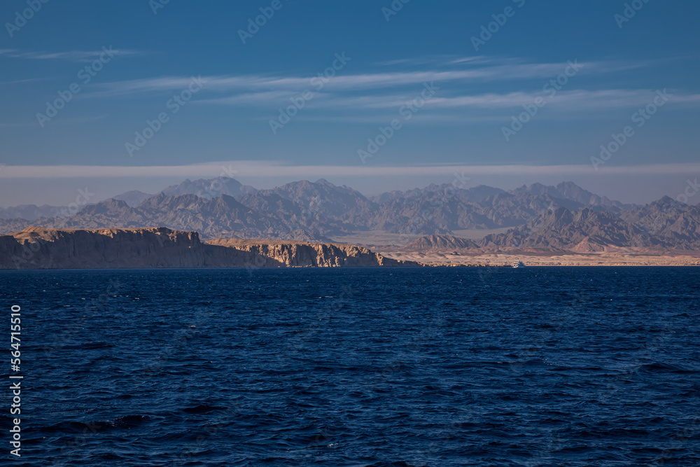 Beautiful blue sea. Sunny evening. Mountains and desert on the coast. Colorful sea landscape.