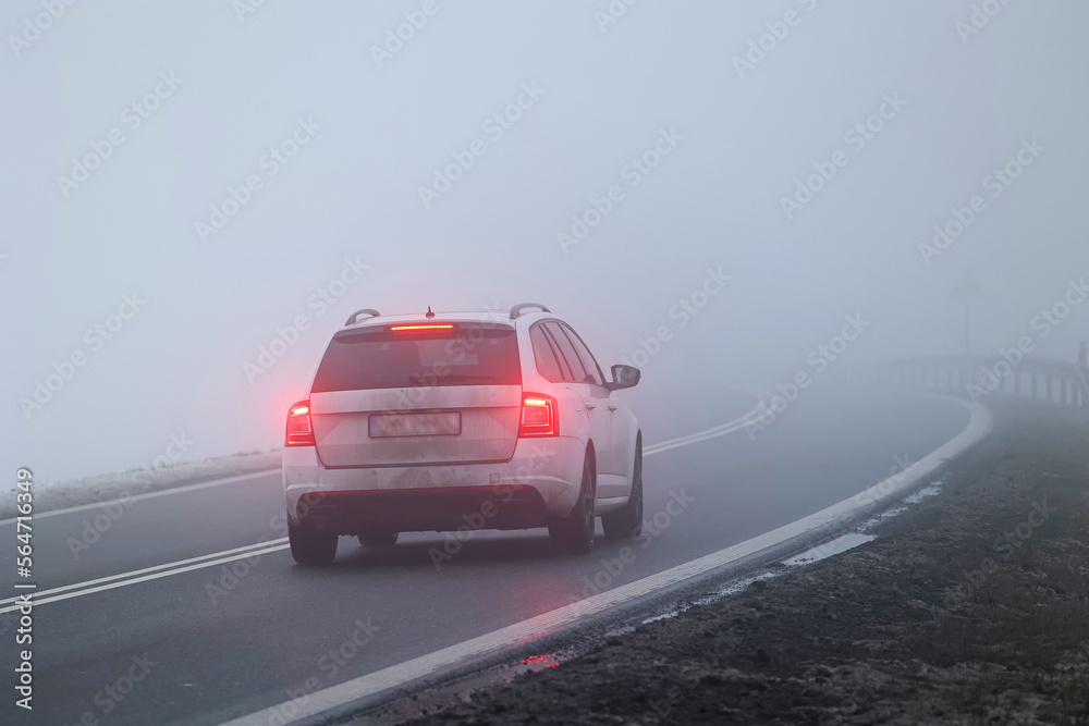 Ruch pojazdów w gęstej mgle na drodze wieczorem. Niebezpiecznie - obrazy, fototapety, plakaty 