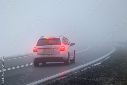 Ruch pojazdów w gęstej mgle na drodze wieczorem. Niebezpiecznie