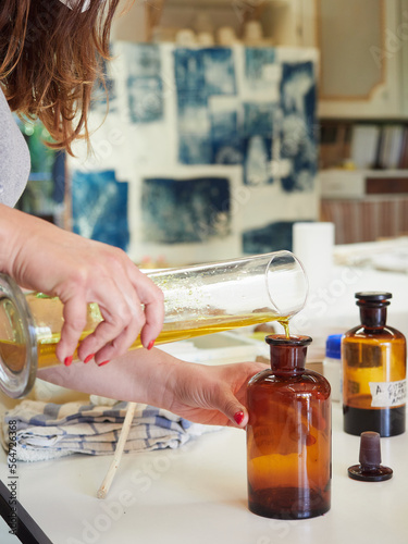 Filling an antique amber bottle with chemical liquid for the cyanotype process. Reaction of ultraviolet light to a chemical mixture. Prussian blue color.