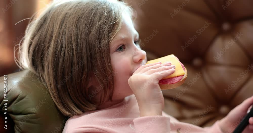 Child lying on sofa and eating delicious sandwich with sausage and cheese 4k movie slow motion Child lying on sofa and eating delicious sandwich with sausage and cheese 4k movie slow motion