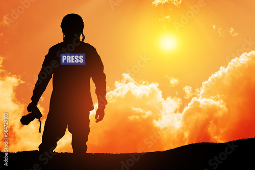 Photojournalist silhouette documenting war or conflict. Photojournalist at sunset. War, army, technology and journalist work concept.
