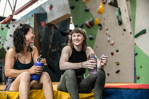 Happy female rock climbers taking a break at climbing gym photo