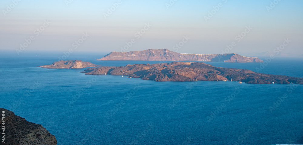 A wide view from The Cliffs of Santorini looking at the ocean and Islands at sunrise A wide view from The Cliffs of Santorini looking at the ocean and Islands at sunrise
