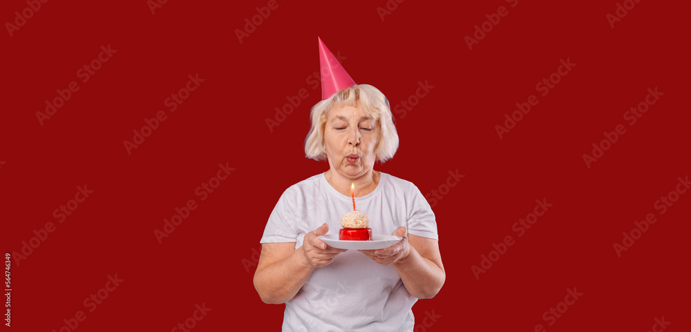 Beautiful happy 50s woman wearing a white t-shirt standing isolated over red background, holding birthday cake with candle on a plate. High quality photo Beautiful happy 50s woman wearing a white t-shirt standing isolated over red background, holding birthday cake with candle on a plate. High quality photo