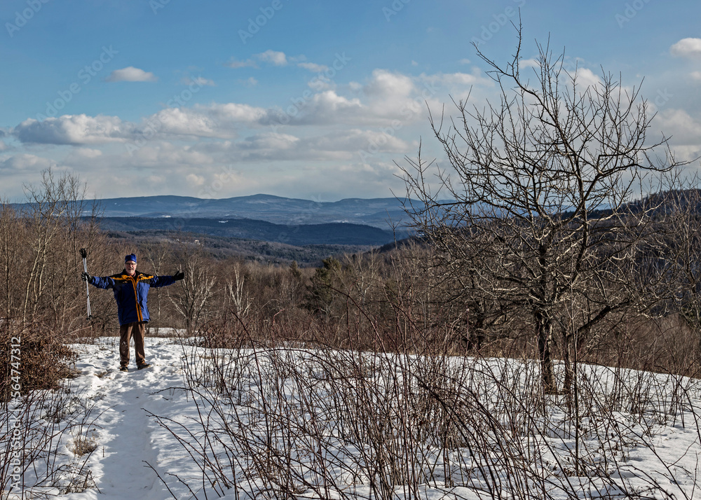 A man celebrates hiking to an overlook in the snow. A man celebrates hiking to an overlook in the snow.