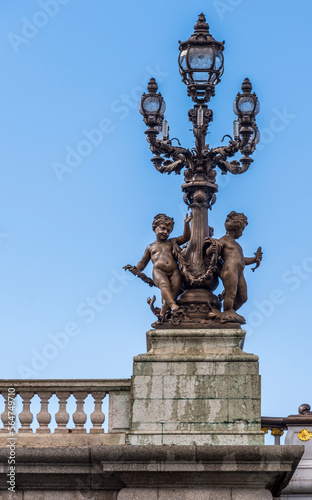 An ornate lamp post with glass globes and cherubs located on the Alexander 3 bridge in Paris France.