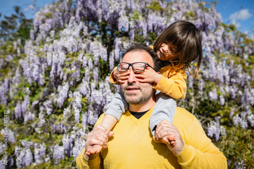 Child sitting on father shoulders closes eyes to a father Child sitting on father shoulders closes eyes to a father
