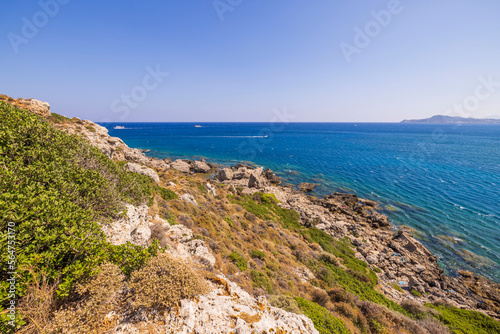 Beautiful landscape view of island on dark blue sea water merging with cloudless sky on background. Rhodes. Greece. 