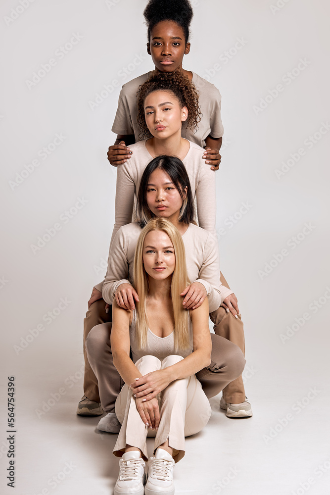 Friendly pleasant women of different ethnicity posing at camera, isolated on white studio background. Portrait of cute models in a row, looking at camera. copy space. people diversity, beauty