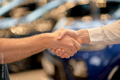 Car Dealership Concept. Close-up Salesperson or Consultant Handshaking With Male Customer In Auto Showroom, Cropepd Unrecognizable Guy Buying New Automobile In Modern Auto Salon. Agreement Shake