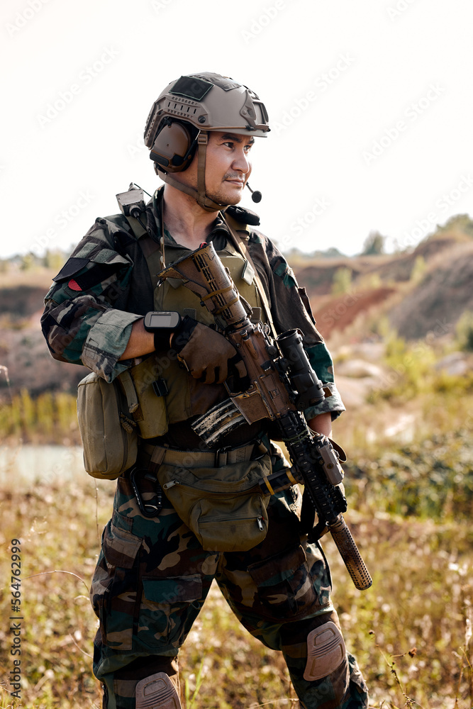 confident army ranger before military operation soldiers against, marine is preparing for war holding assault machine gun, posing at camera alone outdoor, portrait. military forces concept