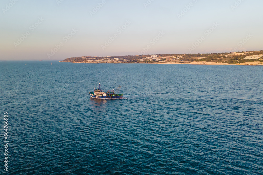 Fototapeta premium Fishing ship equipped with nets and a trawler sails through the azure water