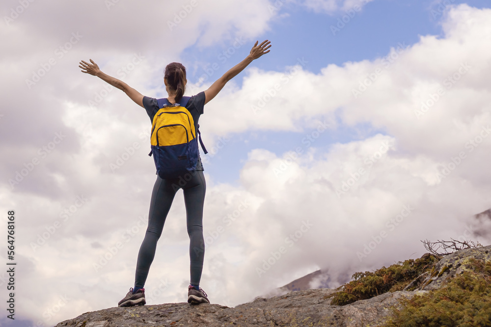 Woman traveller with arms raised on top of mountain looking at view Woman traveller with arms raised on top of mountain looking at view
