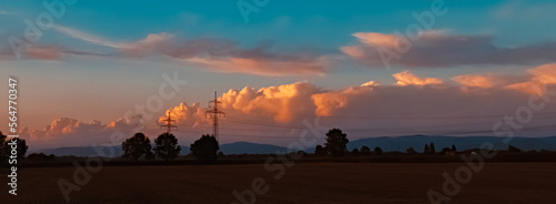 Beautiful sunset with a dramatic sky and overland high voltage lines near Tabertshausen, Bavaria, Germany