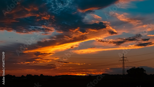 Beautiful sunset with a dramatic sky and overland high voltage lines near Tabertshausen, Bavaria, Germany © Martin Erdniss