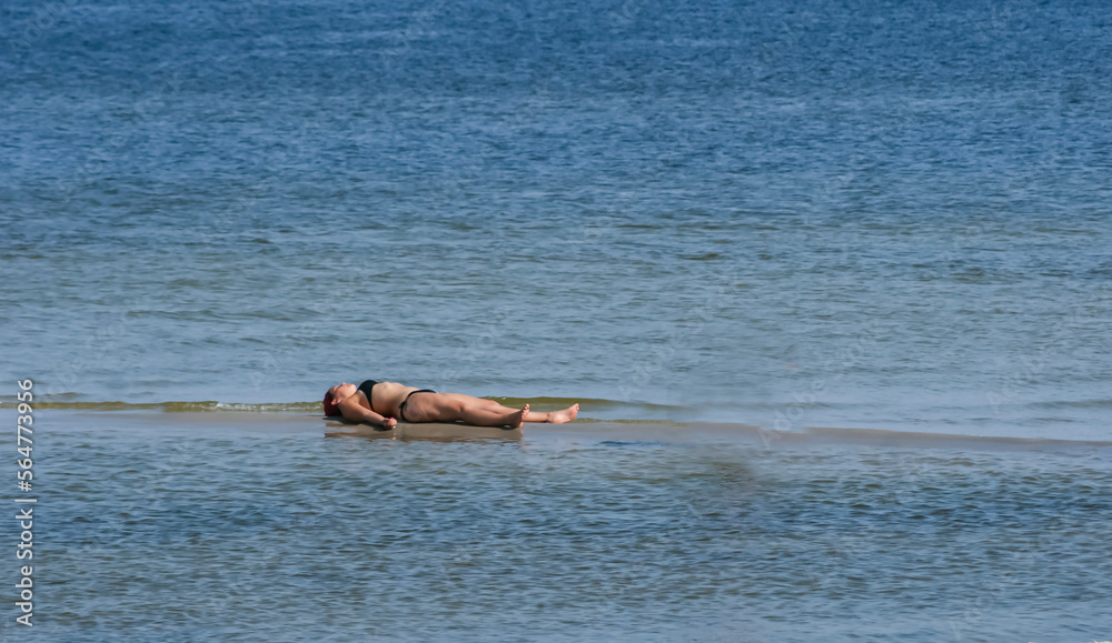 Girl on the shore of the sea of the ocean, lying on the sand sunbathing