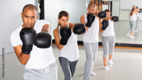 Portrait of diligent serious females and males training in boxing gloves