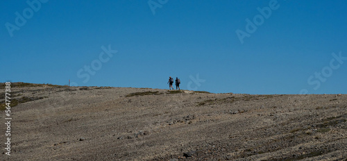 Two active hikers walking on exposed mountain ridge path trail in Nelson Lakes National Park Southern Alps New Zealand