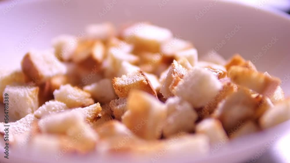 Crackers from white bread are poured into a plate. Bread cubes for cooking. Crackers from white bread are poured into a plate. Bread cubes for cooking.
