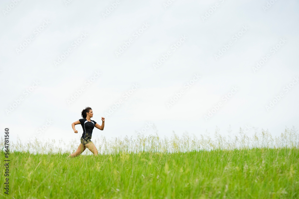 Young woman running on grass trail through a bright green field at Spirit Mound, South Dakota. Young woman running on grass trail through a bright green field at Spirit Mound, South Dakota.