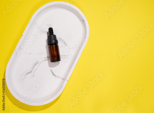 Brown glass bottle with pipette on a yellow background