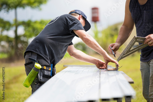 Two men marking measurements on steel excursion for solar panels. photo