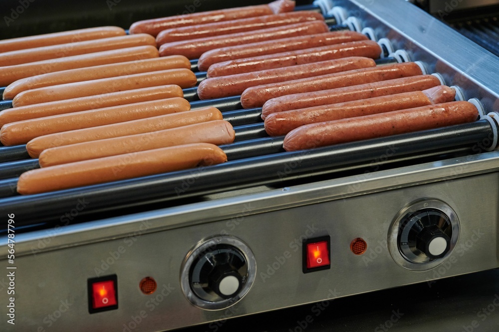 hot dog sausages on rolls of heating device