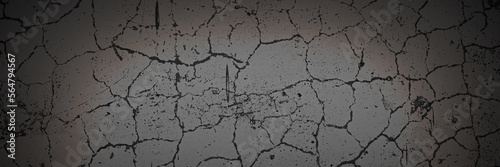 Texture of the old wall. Rough grungy surface of plastered concrete wall with spots, cracks, noise and grain. Dark wide panoramic background for design. Shaded vintage texture with vignette.