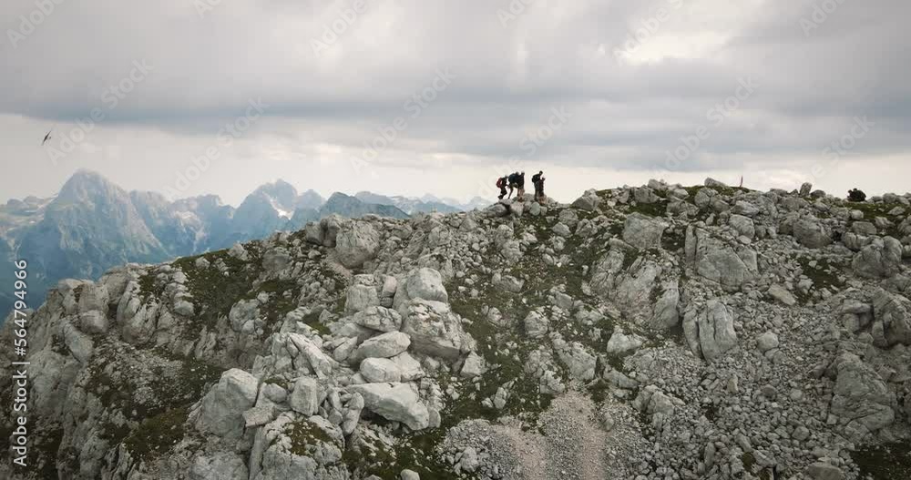 Drone shot of mountain Rombon, a group of hikers walking on the ridge of it towards the top. Clouds covering the sky. Drone shot of mountain Rombon, a group of hikers walking on the ridge of it towards the top. Clouds covering the sky.