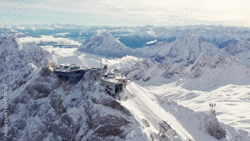 aerial of dramatic mountain summit with glacier in the background and a building on top