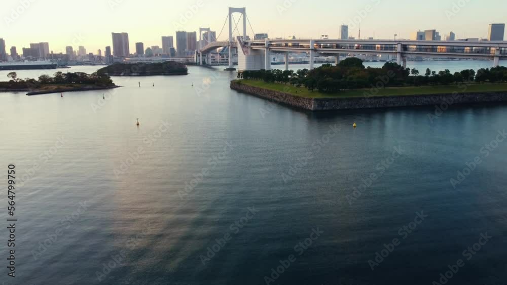 Aerial Drone Flying Low Over Water Revealing Rainbow Bridge In Odaiba Tokyo City During Sunset Aerial Drone Flying Low Over Water Revealing Rainbow Bridge In Odaiba Tokyo City During Sunset